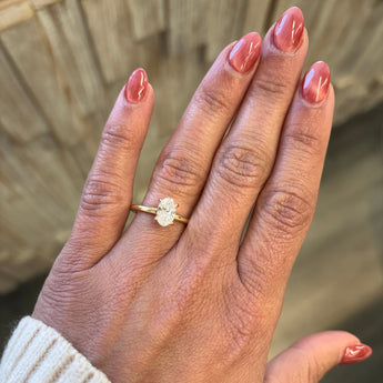 Hand wearing a gold ring with an oval Lab grown diamond on a solitaire engagement ring_Diamond Daughters