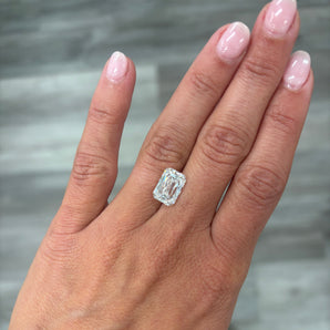 A loose 4.00ct cushion crisscut lab grown diamond resting on the ring finger of a hand