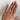 Hand wearing a lab grown diamond on a plain background